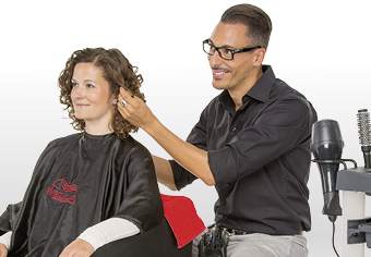 Friseur frisiert die Haare einer Kundin - Münchener Verein Geschäftsinhaltsversicherung